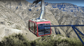 a train is coming down the mountain with Sandia Mountains in the background